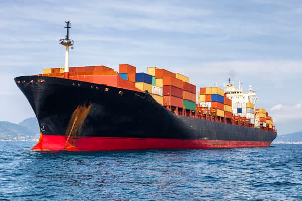 Buque portacontenedores en alta mar con desgaste por corrosión marina en el casco y zona del ancla, requiriendo sistemas de protección epóxica y antiincrustante.