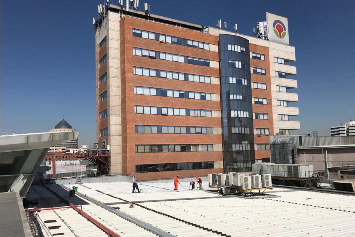 Aplicación de recubrimiento polimérico protector blanco en techumbre metálica de un edificio institucional, previniendo filtraciones, corrosión y mejorando la eficiencia térmica.