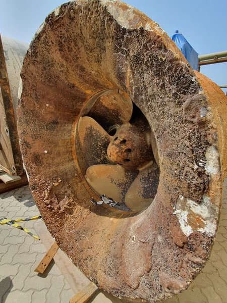Carcasa e impulsor de bomba de flujo axial con severa corrosión, oxidación y picaduras por cavitación, expuesta en un patio industrial antes de su reparación.