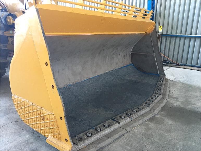 Interior del balde del cargador Caterpillar completamente restaurado y protegido contra la abrasión extrema con METALCLA
