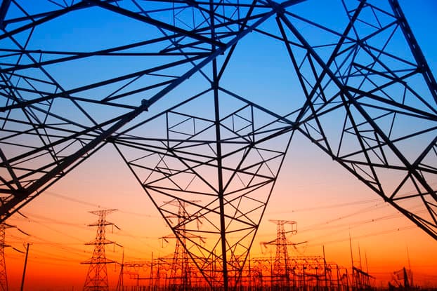 Torres de alta tensión y estructuras de transmisión eléctrica de acero galvanizado contra un cielo de atardecer, expuestas a la corrosión atmosférica.